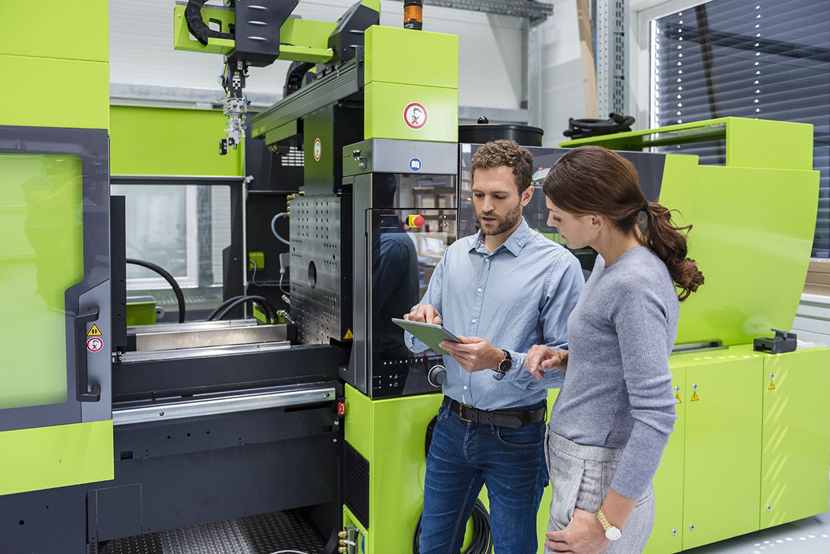 Colleagues In High Tech Company Controlling Manufacturing Machines, Using Digital Tablet