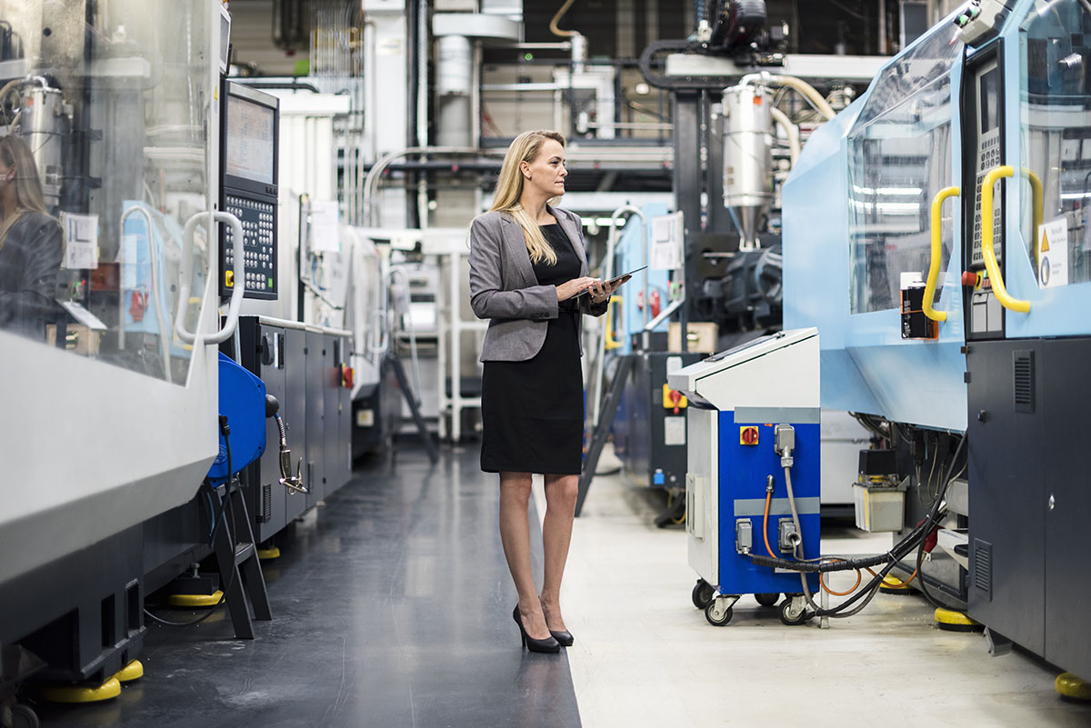 Woman Using Tablet At Machine In Factory Shop Floor